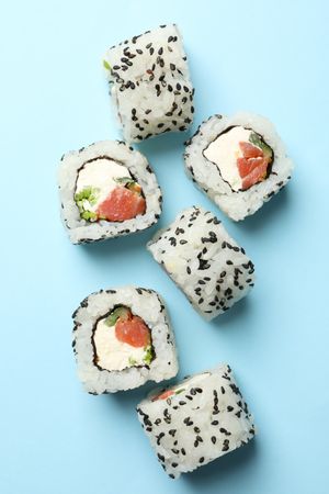 Delicious sushi rolls on blue background. Japanese food