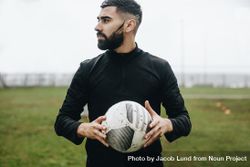 Portrait of a football player standing on field holding a ball looking away 4AJVNb