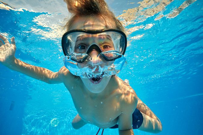 Amazed boy blowing air bubbles in pool