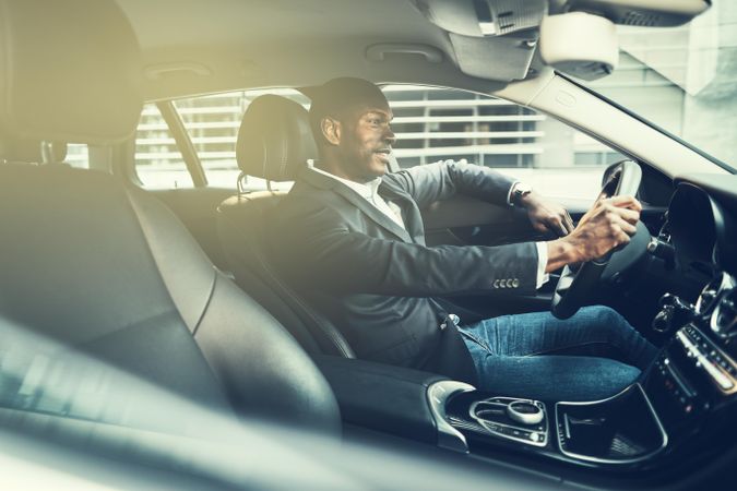 Man in business attire driving luxury vehicle