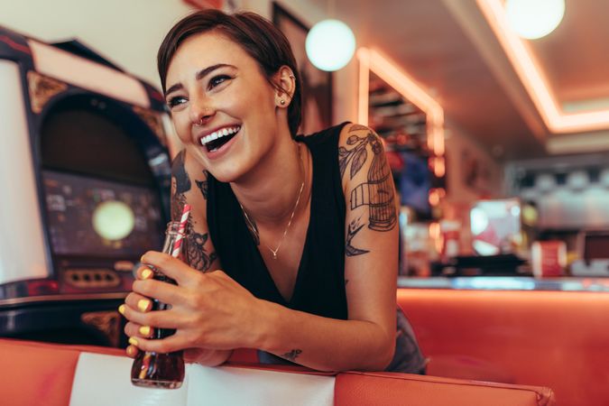 Happy woman standing in a diner smiling and holding a soft drink