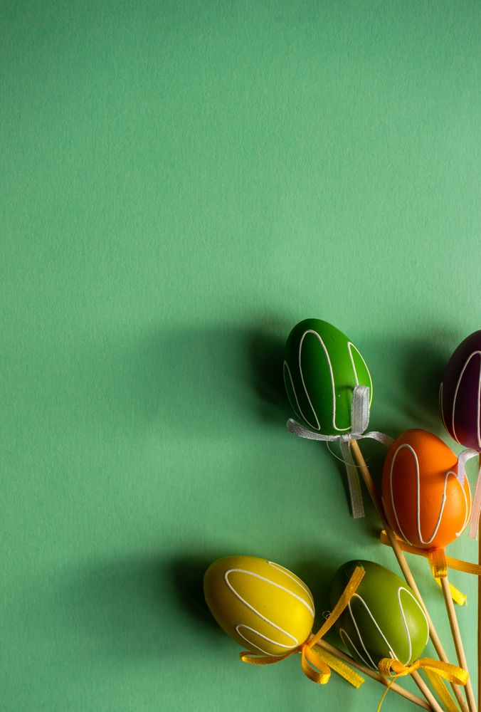 Easter holiday card concept with colorful ornamental eggs scattered on green background
