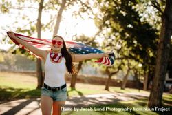 Female in park with USA flag in hands celebrating independence day 4dzzl0