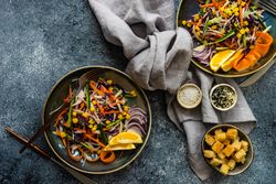 Top view of two fresh salad with finely chopped vegetables and lemon slices in bowl on counter with copy space