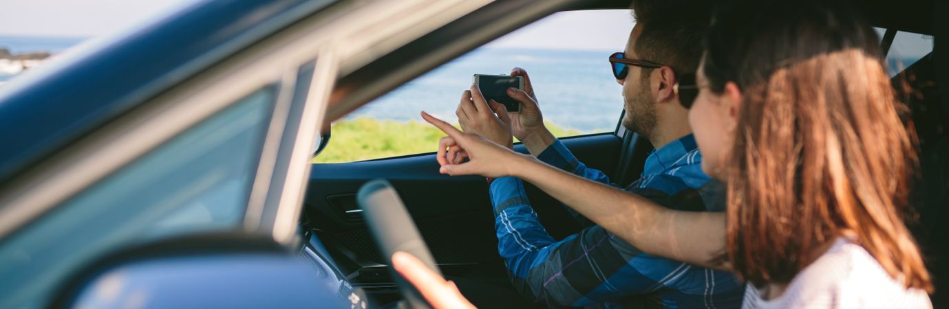 Couple taking picture of landscape from the car