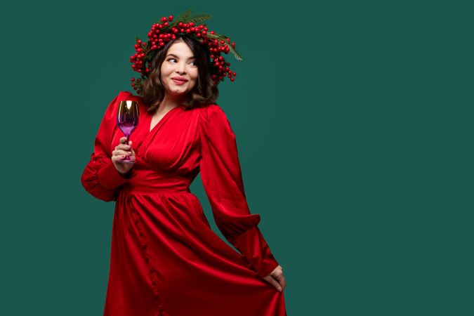 Playful woman in red dress holding wine glass.