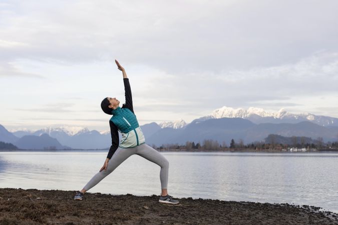 Young woman practicing yoga on the lake shore in the morning