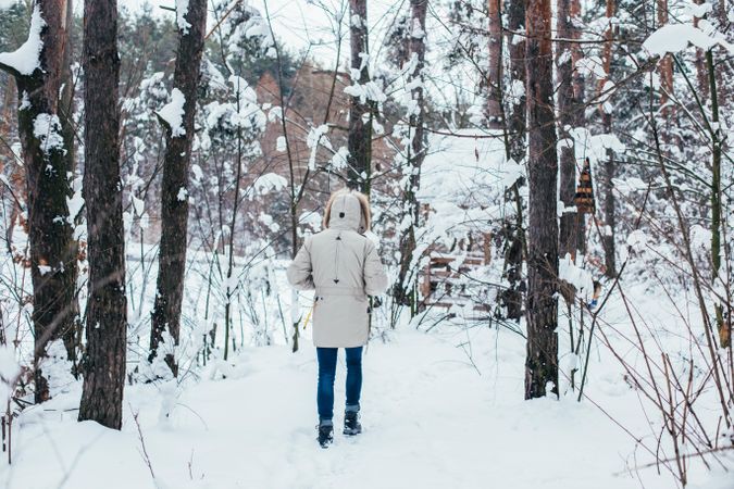 Man in parka outside walking in snowy forest