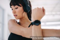 Close up of woman with headphones on stretching her hand at gym 5lm364