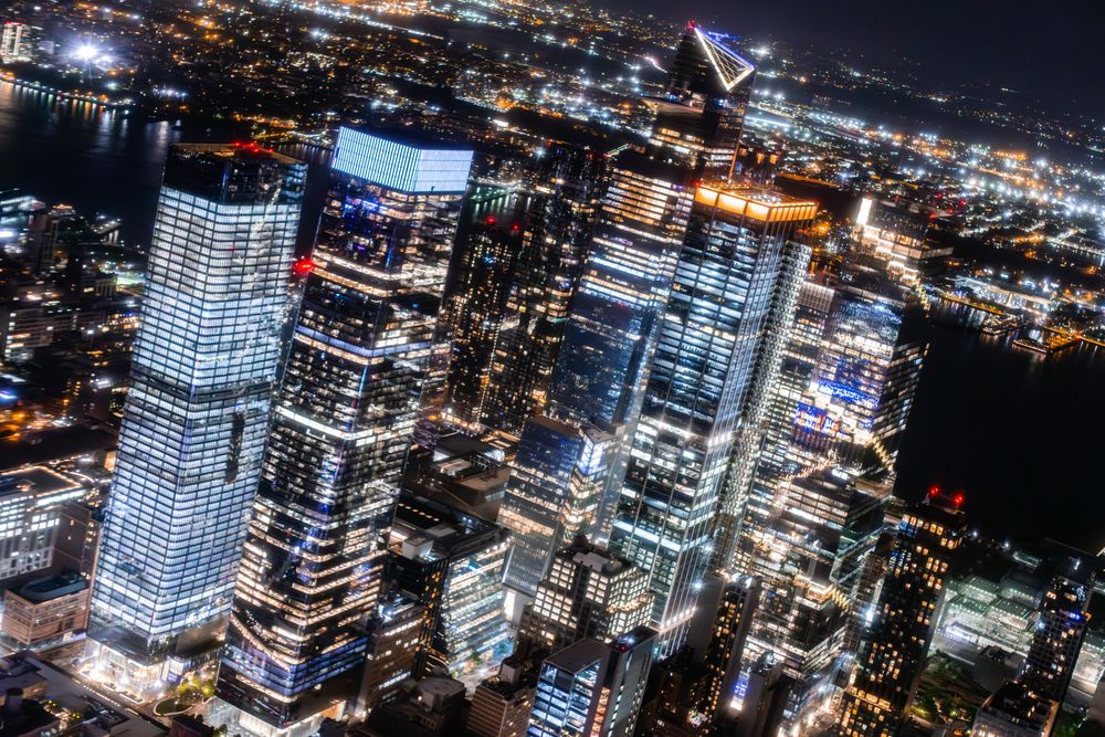 New York City Aerial Night Cityscape with Stunning Manhattan Landmarks, Skyscrapers and Residential Buildings. Wide Angle Panoramic Helicopter View of a Popular Travel Destination