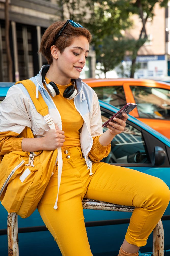 Stylish young woman using smartphone on street in downtown