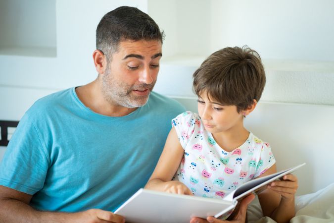 Dad with girl reading together at home