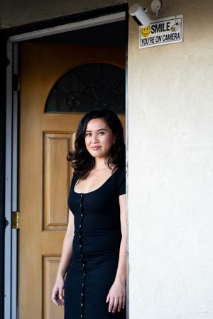 Portrait of woman in darkdress smiling and looking at camera at front door
