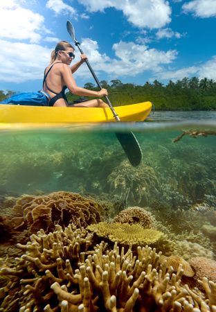 Sportive woman traveling on canoe in tropical lagoon