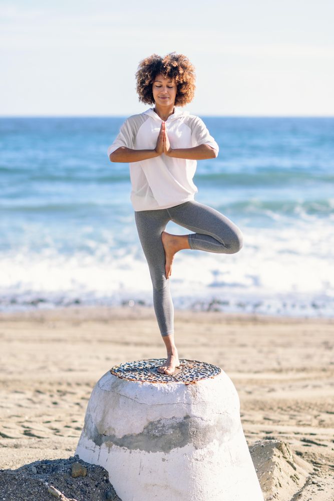 Black woman doing yoga in the beach
