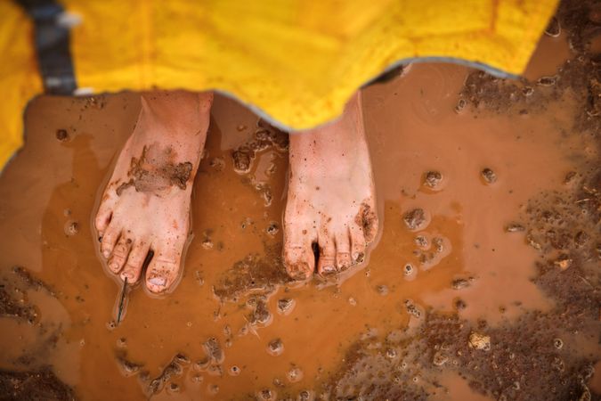 Dirty feet of crop person in puddle