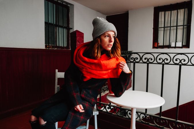 Pensive woman in warm wear sitting near steps in house