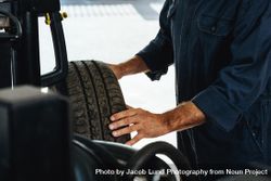Man examining the wear and tear of car tire in garage 41Xv75