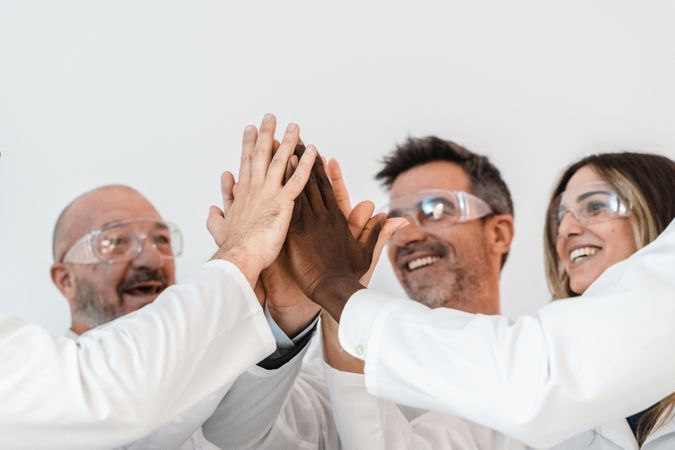 Group of joyful scientists high-fiving in a lab, showcasing teamwork and diversity in research