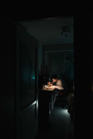 Young man studying in a dark room