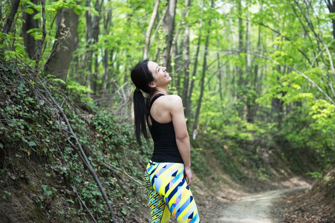 Athletic female smiling in colorful leggings in the forest