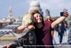Blonde female and curly haired boyfriend taking selfie on bridge in London 5QrkG4