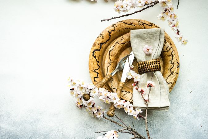 Top view of spring floral concept with top view of apricot blossom branches surrounding brown plates on grey table