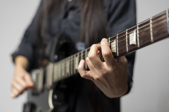 Close up of a female guitarist's hands while playing chords on the electric guitar