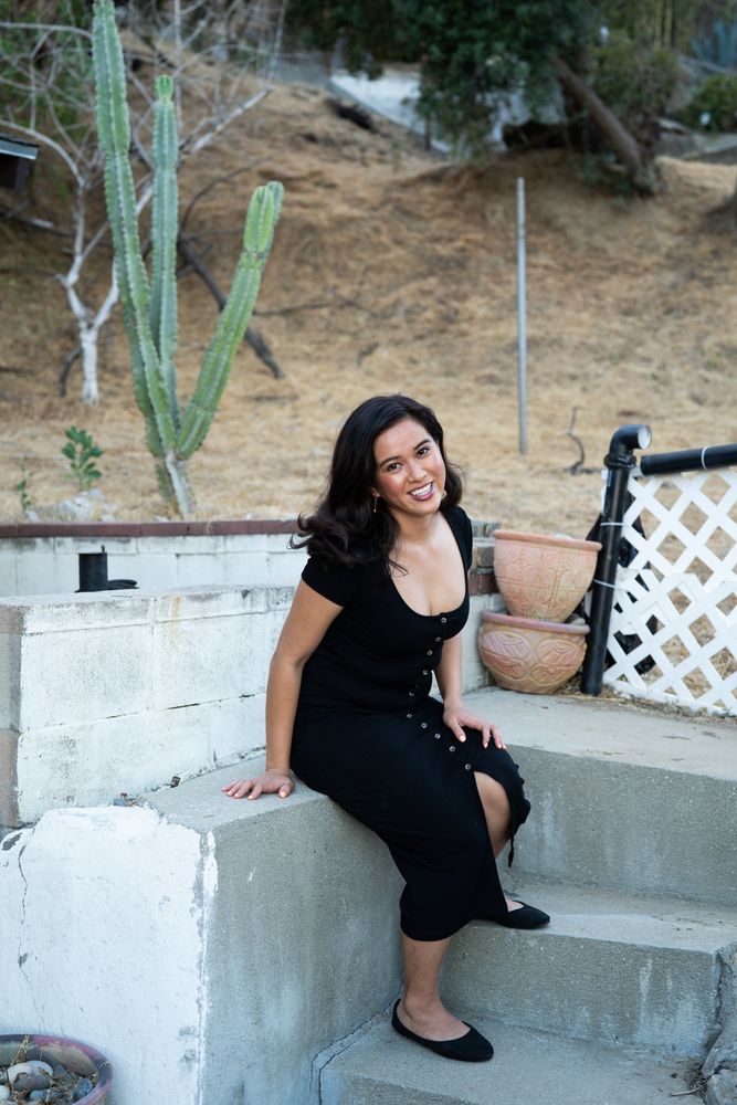 Full length portrait of woman smiling and leaning toward camera outside in front of cactus