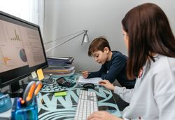 Mother helping her son with his homework while teleworking