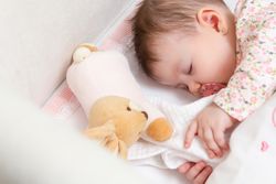 New born baby girl sleeping in a cot with pacifier and toy