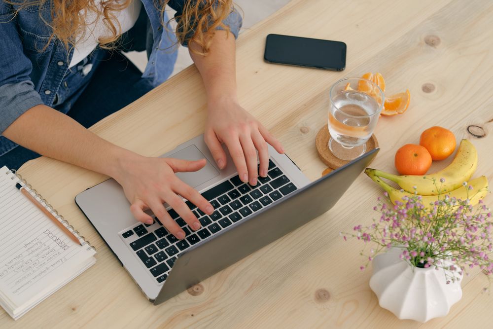 Crop woman working on laptop at home