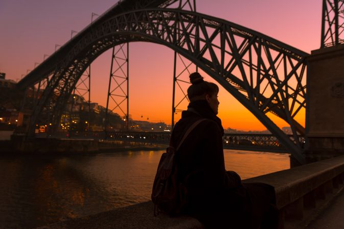 Woman looking at river and city in evening