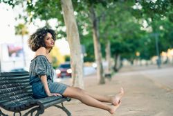 Contemplative female in casual dress sitting on park bench and thinking