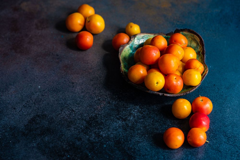 Bowl of plums on dark counter