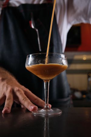Unrecognizable barman preparing coffee cocktail in bar