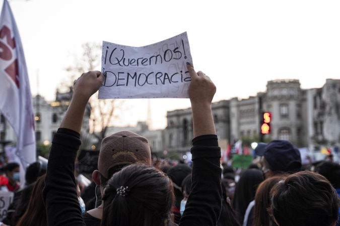 Person holding a banner with text saying " Queremos Democracia" at protest against unconstitutional Merino's Peruvian president