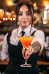 Young female bartender offering a drink