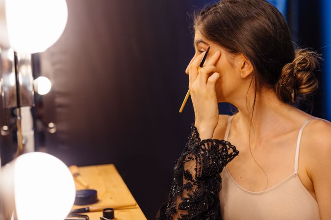 female in peignoir applying makeup