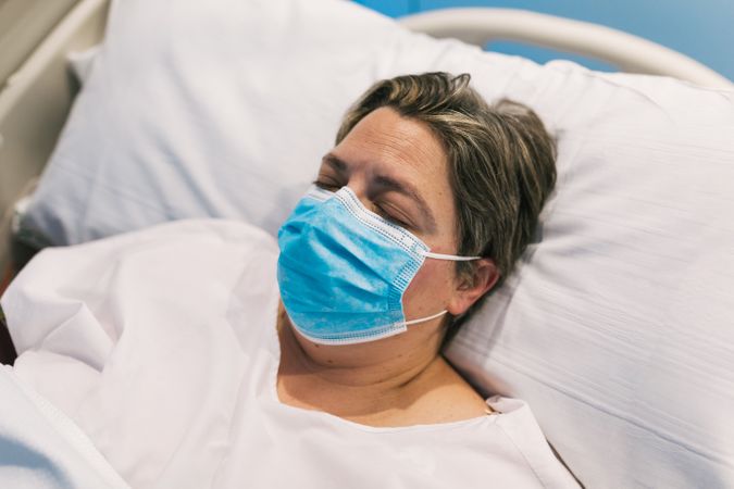Plump woman in mask sleeping on hospital bed