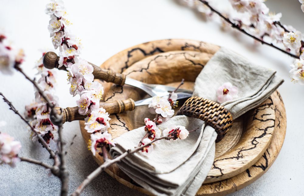 Table setting of apricot blossom branches surrounding brown plates on grey table