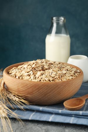 Composition with oatmeal flakes and milk on gray background. Cooking breakfast