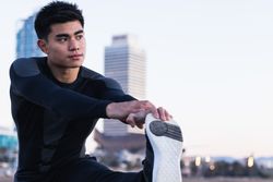 Asian man stretching legs during outdoor workout
