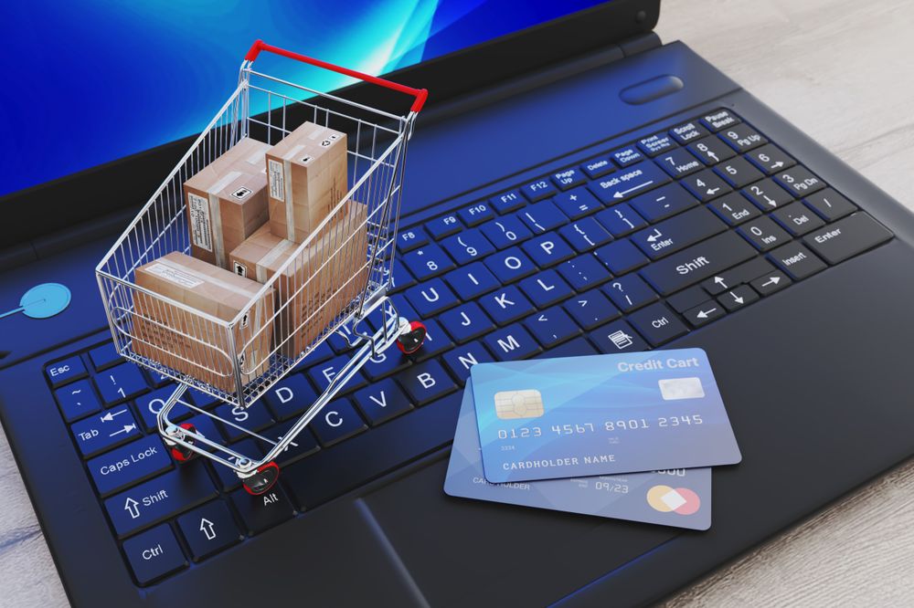 Online Shopping Concept with Cart, Packages, and Credit Cards on Laptop