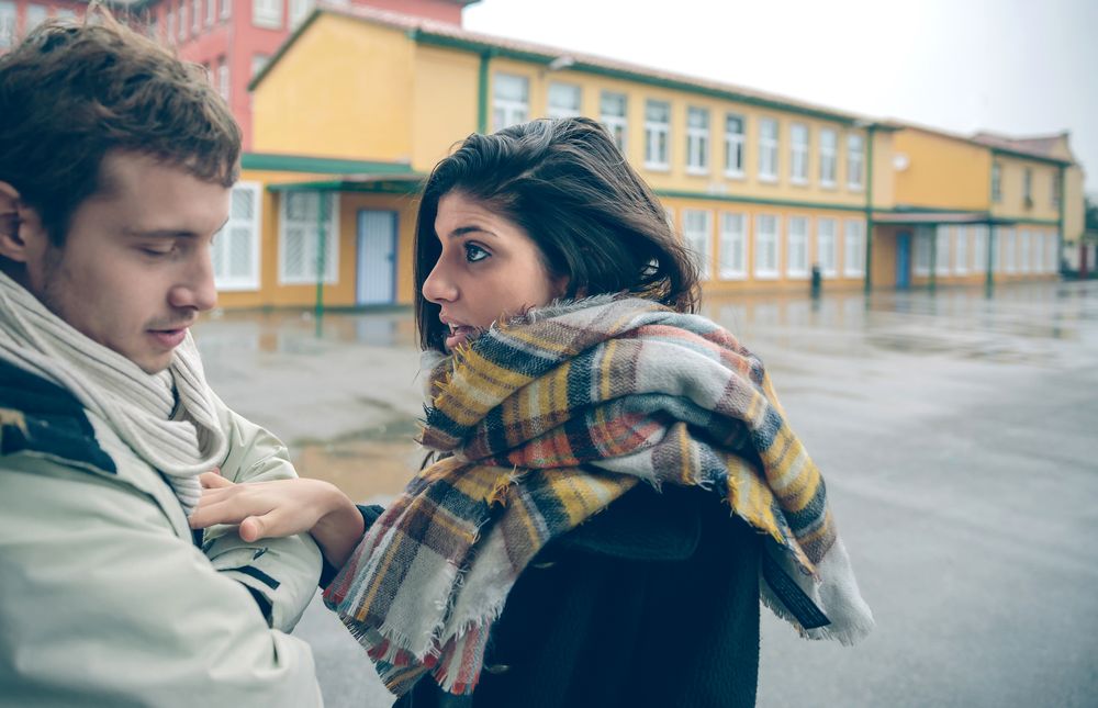 Woman confronting man outside on cold autumn day