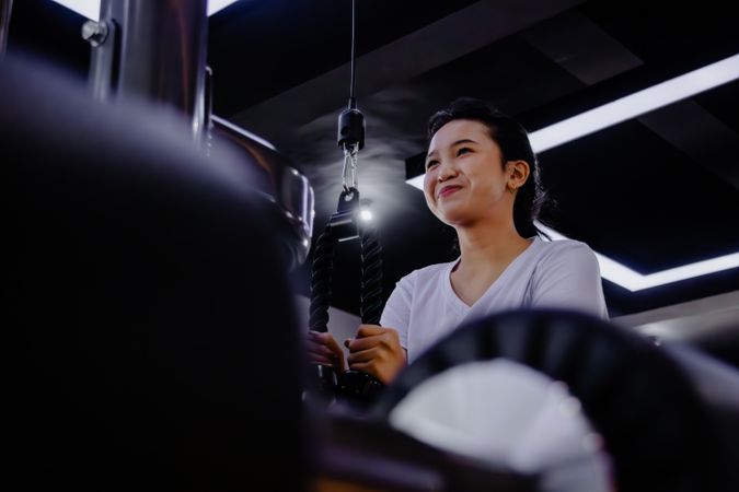 Determined woman using cable machine for training triceps at the gym