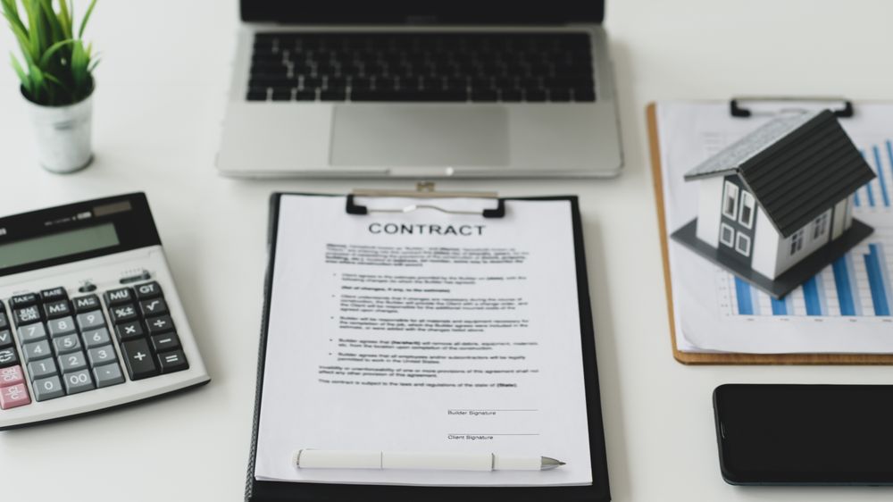 Work desk for signing house construction contract documents with model house on graph and notebook