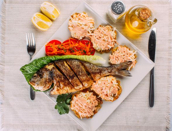 Top view of fried fish, salad and fried plantain