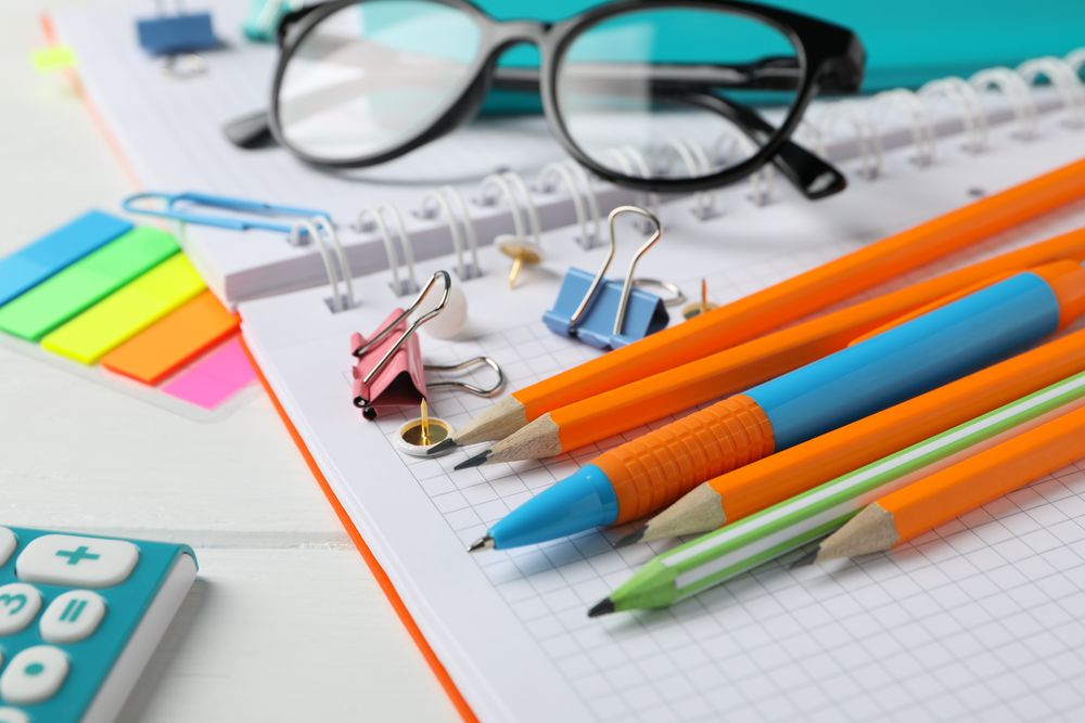 Stationary pens and pencils on notebook on table