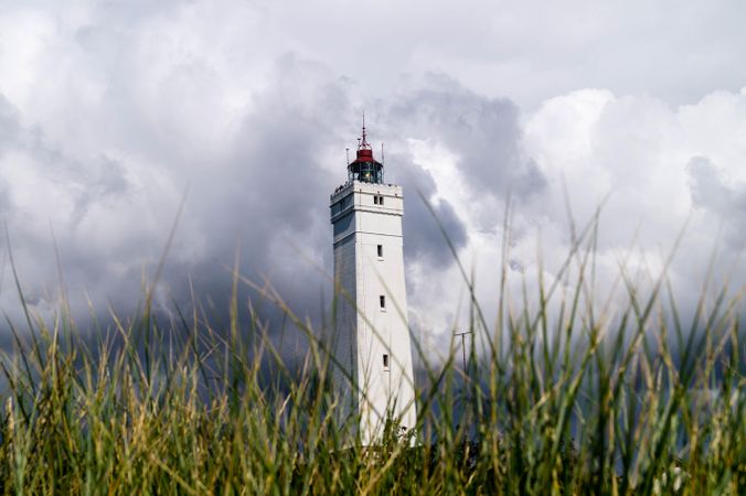 Lighthouse  surrounded on green grass field under cloudy sky